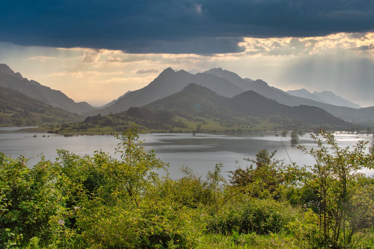 Majestic view of Riaños lush mountains and serene lake under dramatic skies.
